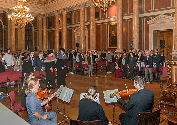 Participants of the ceremony standing up accompanied by String Quartet